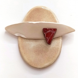 Pieza de cerámica plana ovalada, compuesta por tres elementos. Uno grande de color cremoso sobre el que están uno más pequeño blanco, plano, y una pieza pequeña roja